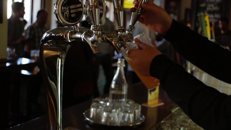 Una brocca di birra che viene versata in un pub affollato