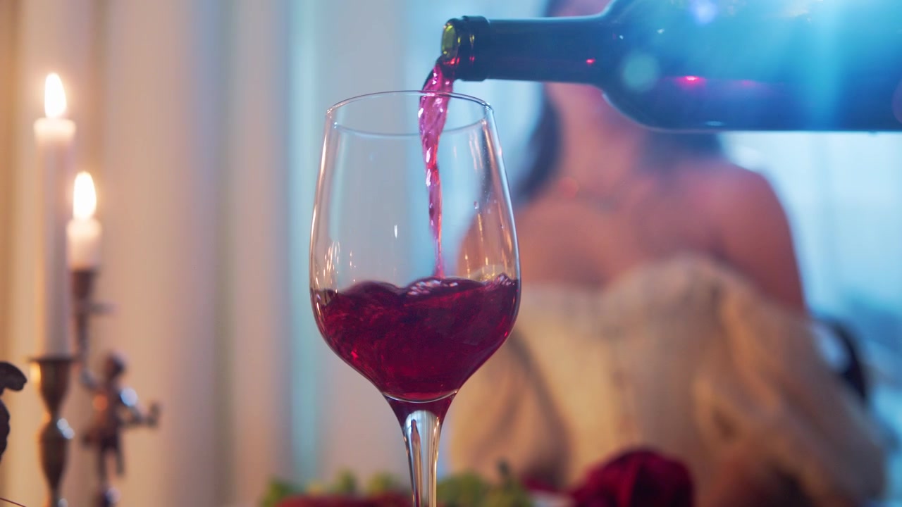 Vino tinto sirviéndose en copa con mujer elegante en un entorno romántico