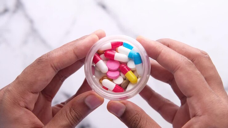 Hands holding a jar of assorted pills