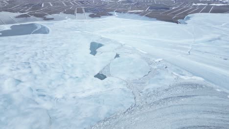 Snowy-Mountains-And-Frozen-Lake-With-Cracks-During-Winter-In-Iceland