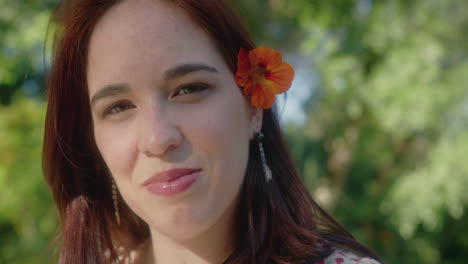 mujer con una flor de naranja detrás de su oreja izquierda sonriendo