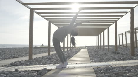 woman practicing backbend yoga on a beach