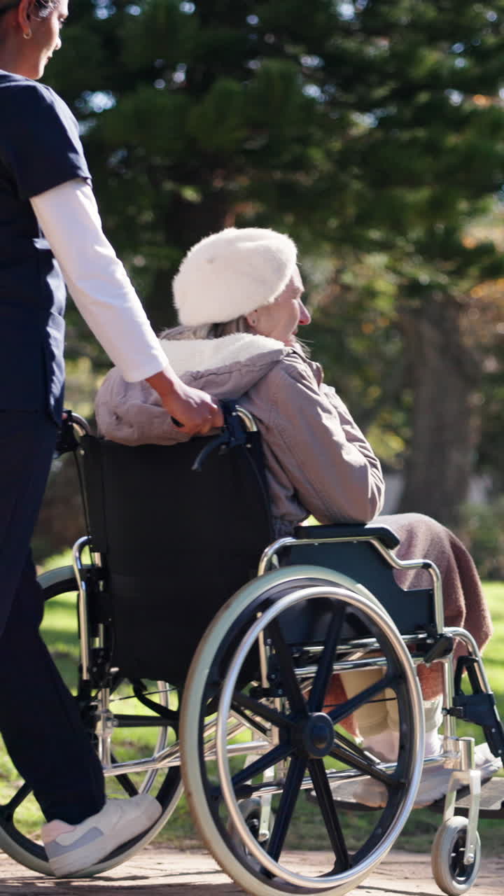 Badante che spinge una donna anziana su sedia a rotelle in un parco