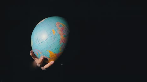 girl's hands twist the geographic globe around its axis