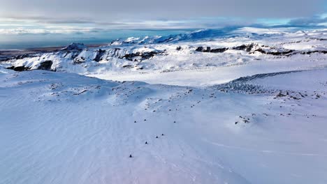 Luftlandschaftsaufnahme-Von-Menschen,-Die-Mit-Schneemobilen-Auf-Dem-Myrdalsjökull-Gletscher-In-Island-Fahren,-In-Der-Abenddämmerung