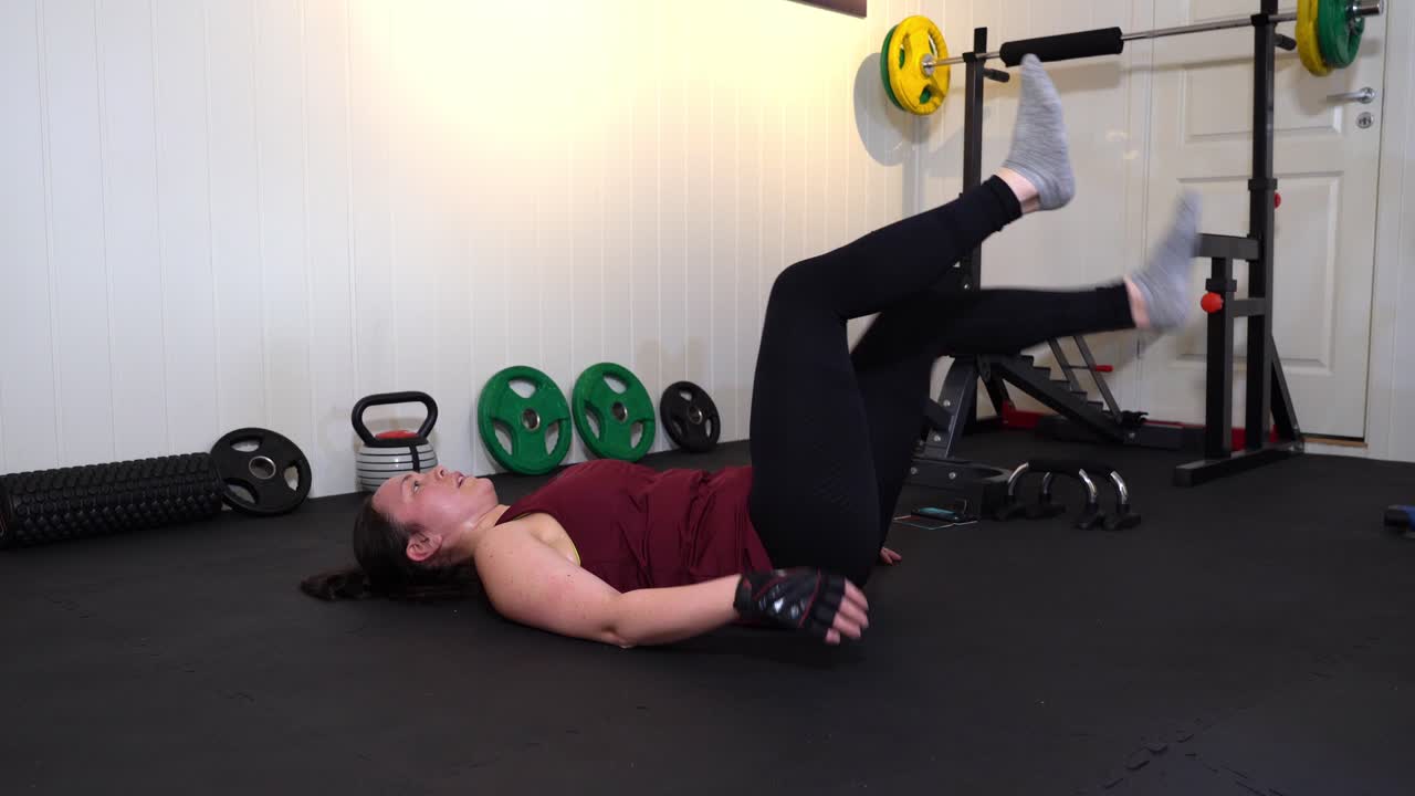 ejercicio de fuerza de piernas realizado por una feliz mujer sonriente en un pequeño gimnasio