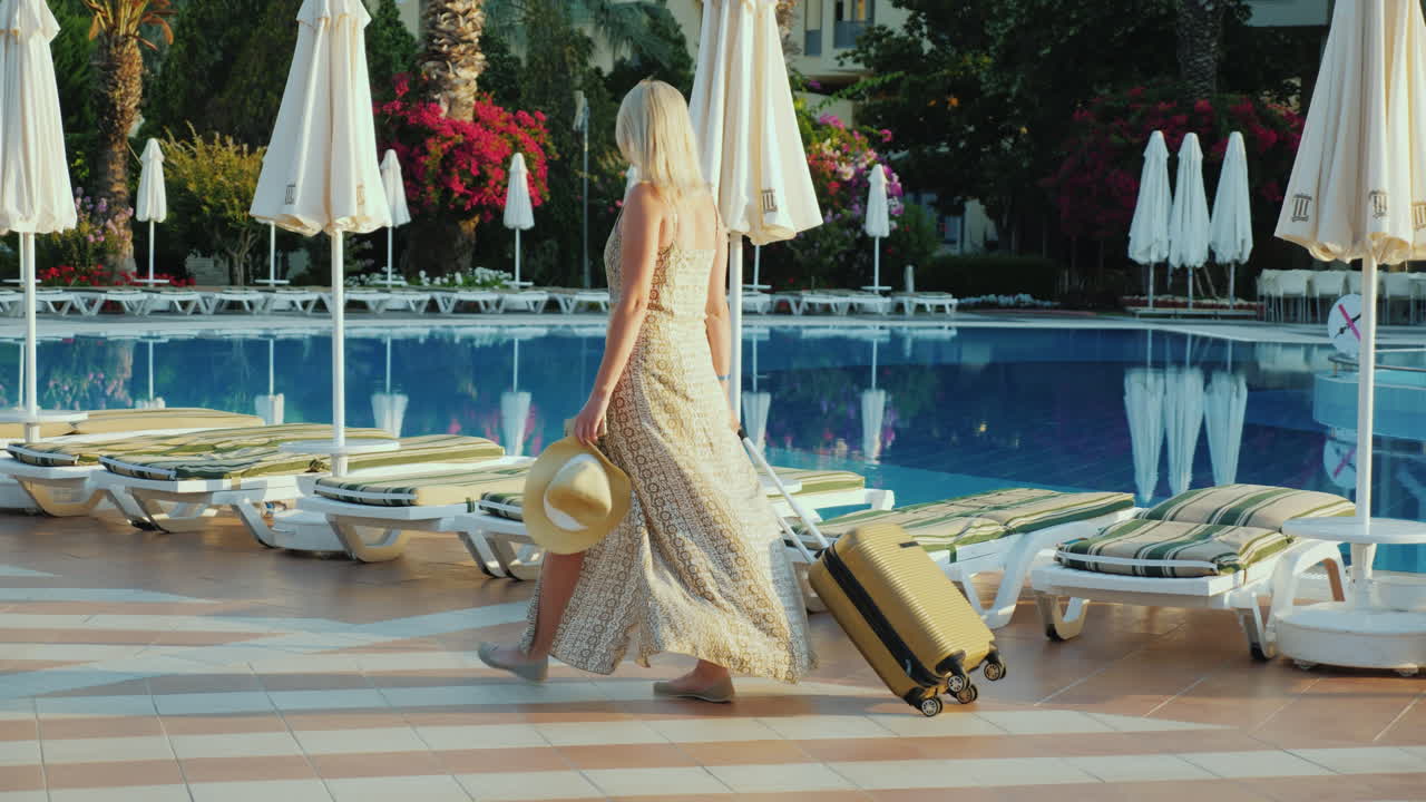женщина с дорожной сумкой поселилась в отеле-курорте на время отпуска, проходя мимо бассейна