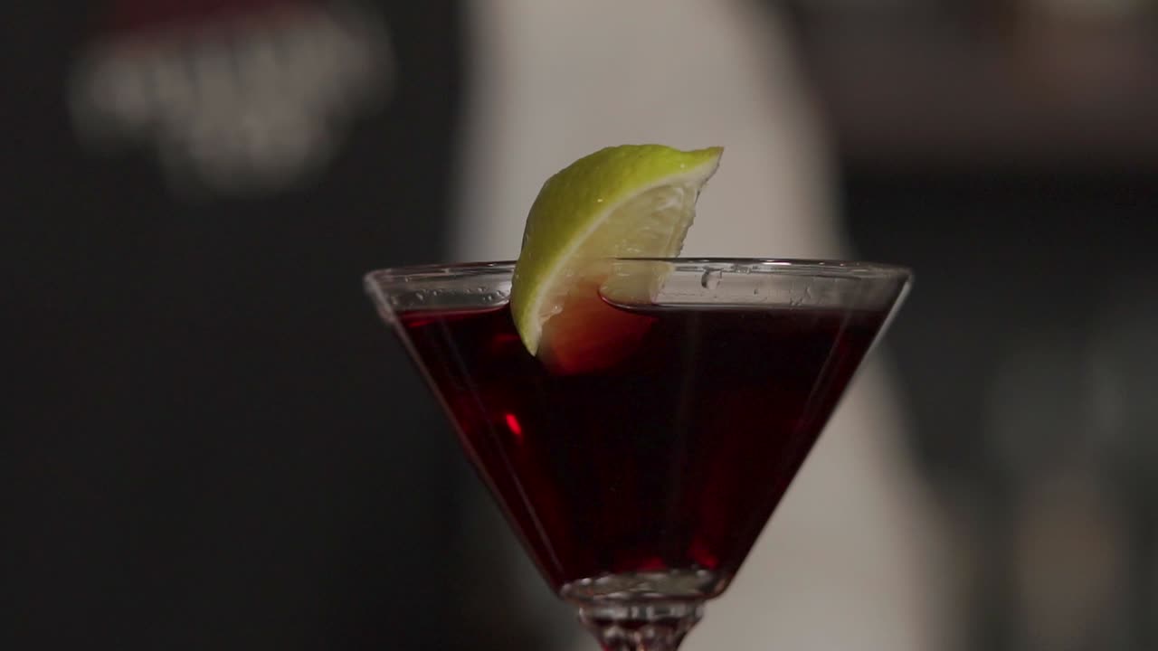preparando un cóctel rojo con guarnición de lima