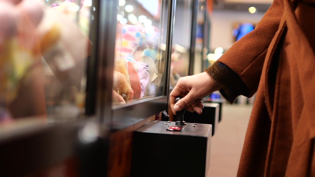 Persona che gioca a una macchina a gru in sala giochi