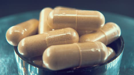 a macro shot in a lab of a medical capsules, organic pills on a rotating stand in a black shiny bowl, studio light, 4k video