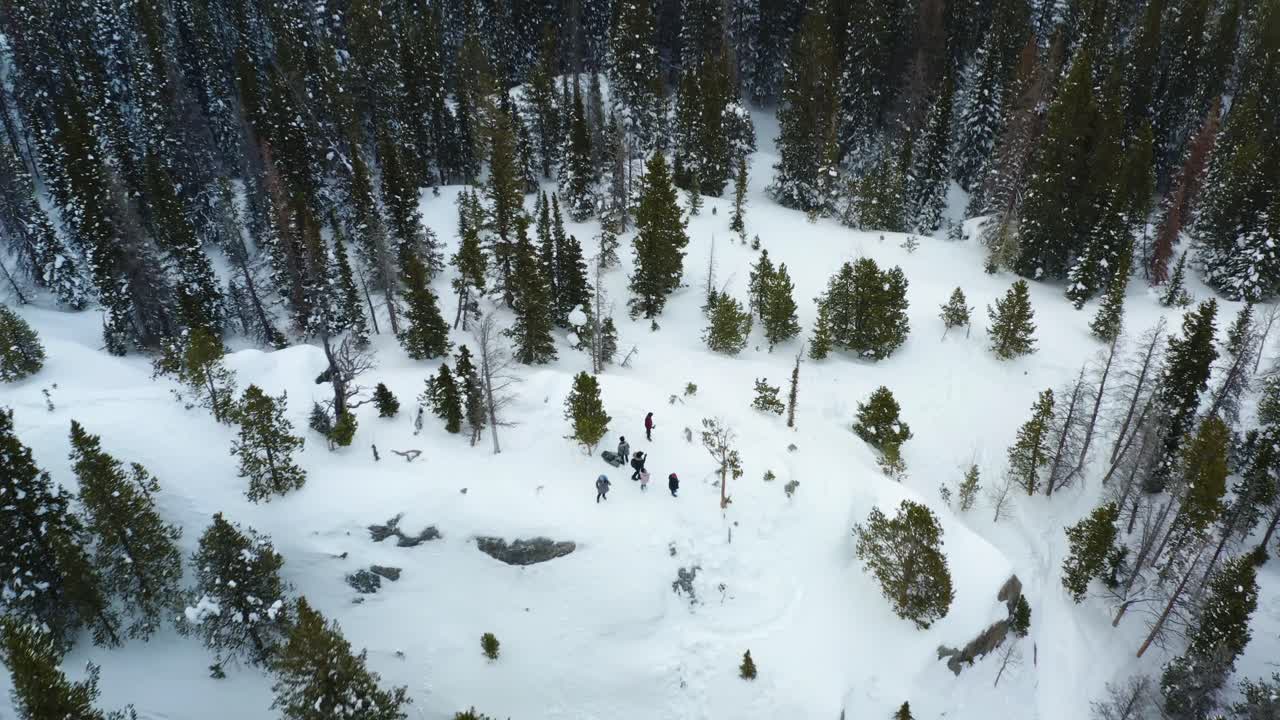 Panoramica aerea in avanti e in basso di un gruppo di persone su una montagna innevata
