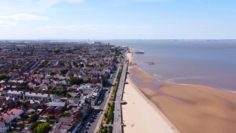 Aerial-view-heading-along-Grimsby-Cleethorpes-seaside-town-coastline-towards-holiday-pier-landmark