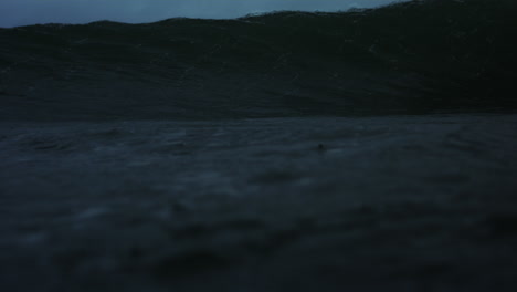 frontal view of lip of ocean wave crashing into dark deep churning barrel tube of green water