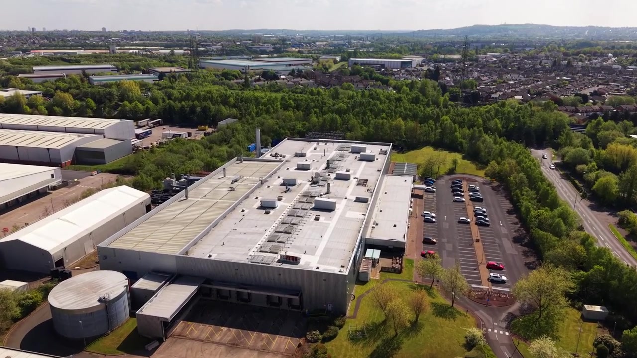 Drone flyover above industrial warehouses and business units in England. Aerial footage of commercial estate, logistics facilities and urban industrial infrastructure.