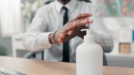 man in white shirt and tie squeezes liquid from dispenser, disinfects hands before touching computer keyboard office hygiene and safety