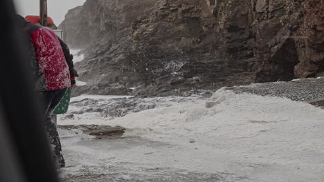 mujer cubierta de nieve como la espuma del mar durante la tormenta de invierno extremo eunice en la costa de la playa de chapel porth en cornualles, reino unido