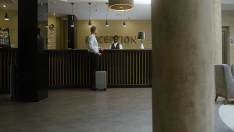 Man-checking-in-at-the-hotel-reception-desk