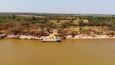 Los-Coches-Esperan-Para-Abordar-Un-Ferry-Fluvial-Para-Cruzar-El-Río-Tsiribihina-En-Madagascar,-Vista-Aérea-De-Drones-Con-Toma-Amplia