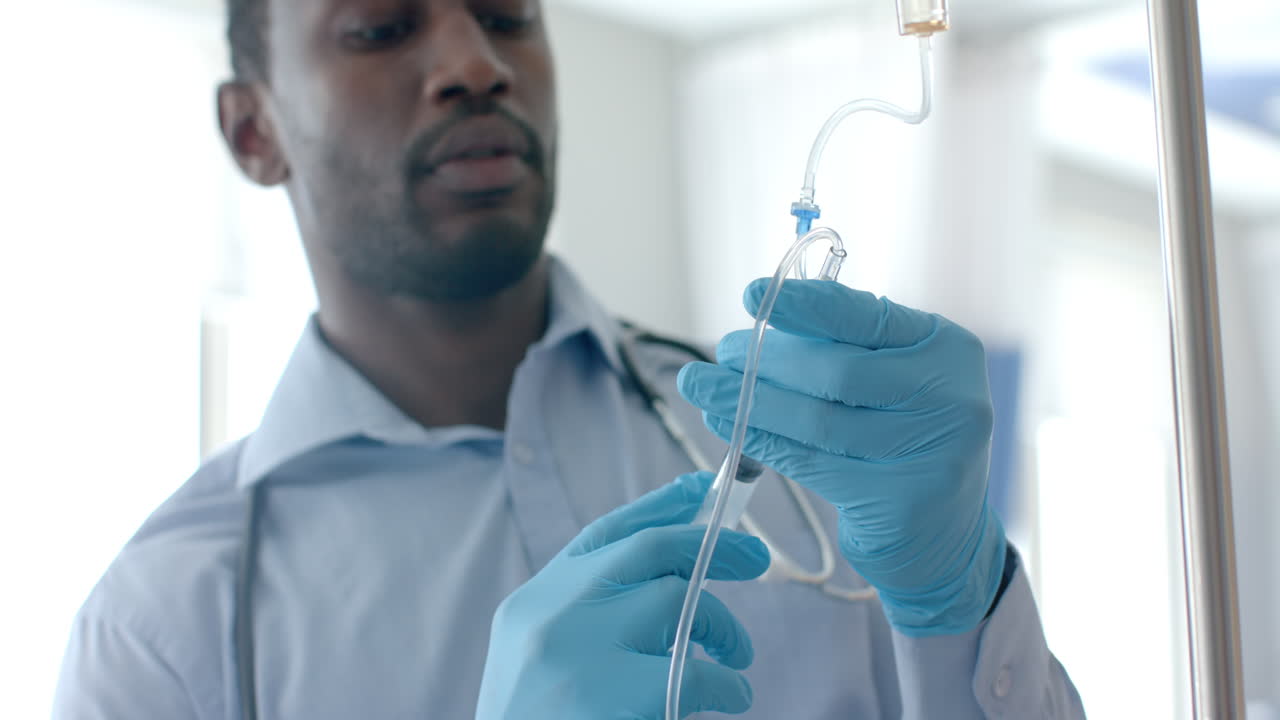 Focused african american male doctor in gloves injecting drip of patient with syringe, slow motion