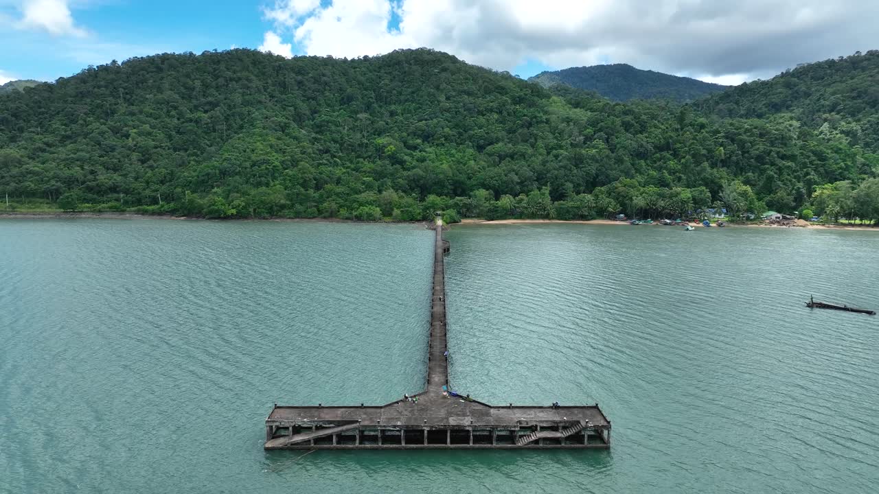 Aerial view of Than Mayom Pier stretching into the calm turquoise waters on Koh Chang Island, Trat, Thailand, surrounded by lush green hills and tranquil coastal scenery