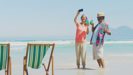 Vorderansicht-Eines-Aktiven-älteren-Afroamerikanischen-Paares,-Das-Am-Strand-Ein-Selfie-Mit-Dem-Mobiltelefon-Macht,-4K