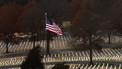 drone establishing shot of waving american flag on large fayetteville national cemetery, arkansas, usa