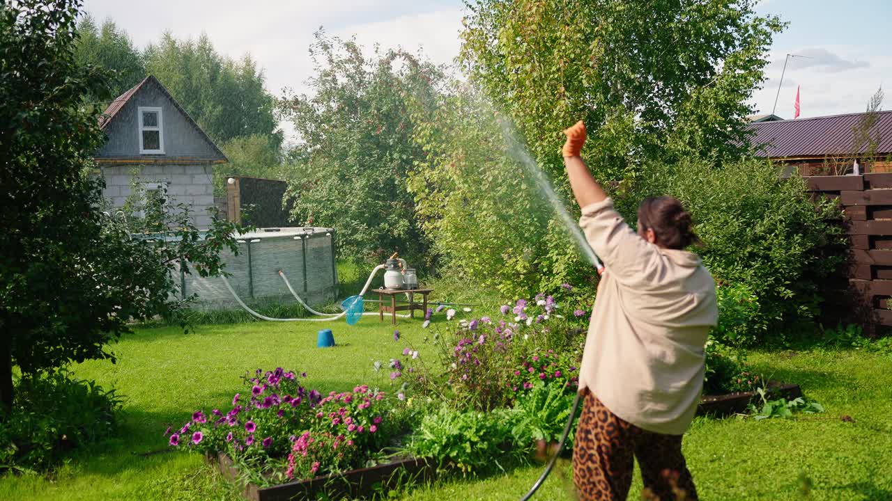 A Gardener Watering Vibrant Flowers in a Lush Green Yard, Showcasing a Beautiful Outdoor Setting with a Simple Home in the Background on a Sunny Day