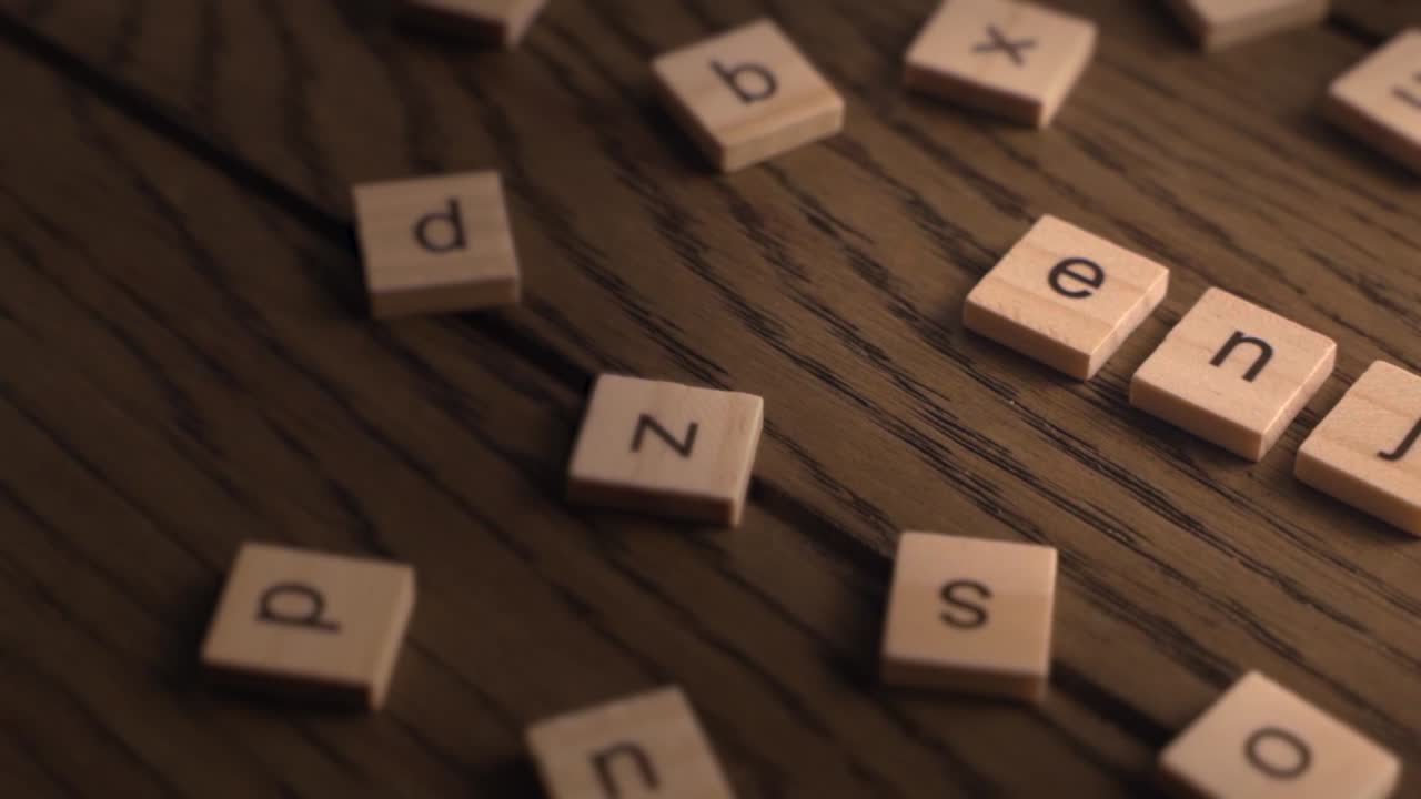 Wooden tiles spell the word enjoy while the camera pans slowly across a rustic wooden surface.