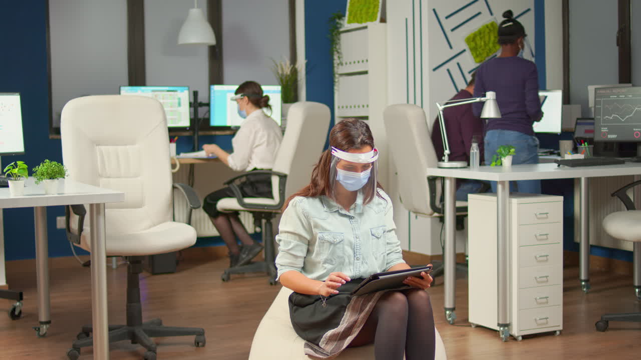 Empresária sentada no meio de uma sala de escritório segurando um tablet digital