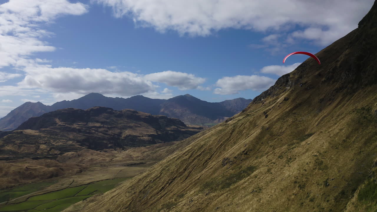 parapente en wanaka nueva zelanda a través de las montañas y colinas con vistas a un lago cerca del pico roys