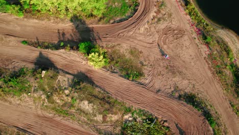 sunshine day aerial over motorbikes doing exercise in off-road ground near the river bank