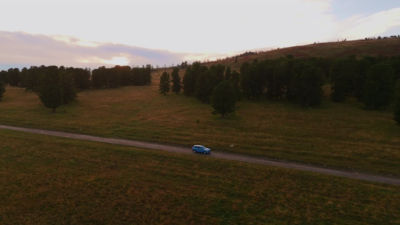 Ripresa aerea di un'auto su una strada forestale con un bellissimo tramonto. Vista laterale