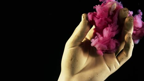 close up of plaster hand placed underwater with pink ink drops spreading around. stock footage. concept of art, hand statue and colorful paints on black background