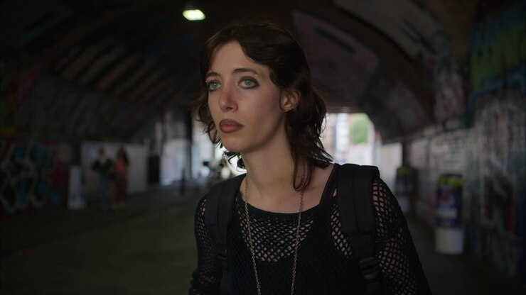 Anxious Young Alternative Style Woman Walking Along Dark Underpass With Graffiti Covered Walls On London City Street UK In Real Time 1