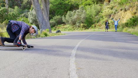 Vista-Frontal-De-Un-Joven-Caucásico-Fresco-Haciendo-Truco-De-Patineta-Cuesta-Abajo-En-Una-Carretera-Rural-4k