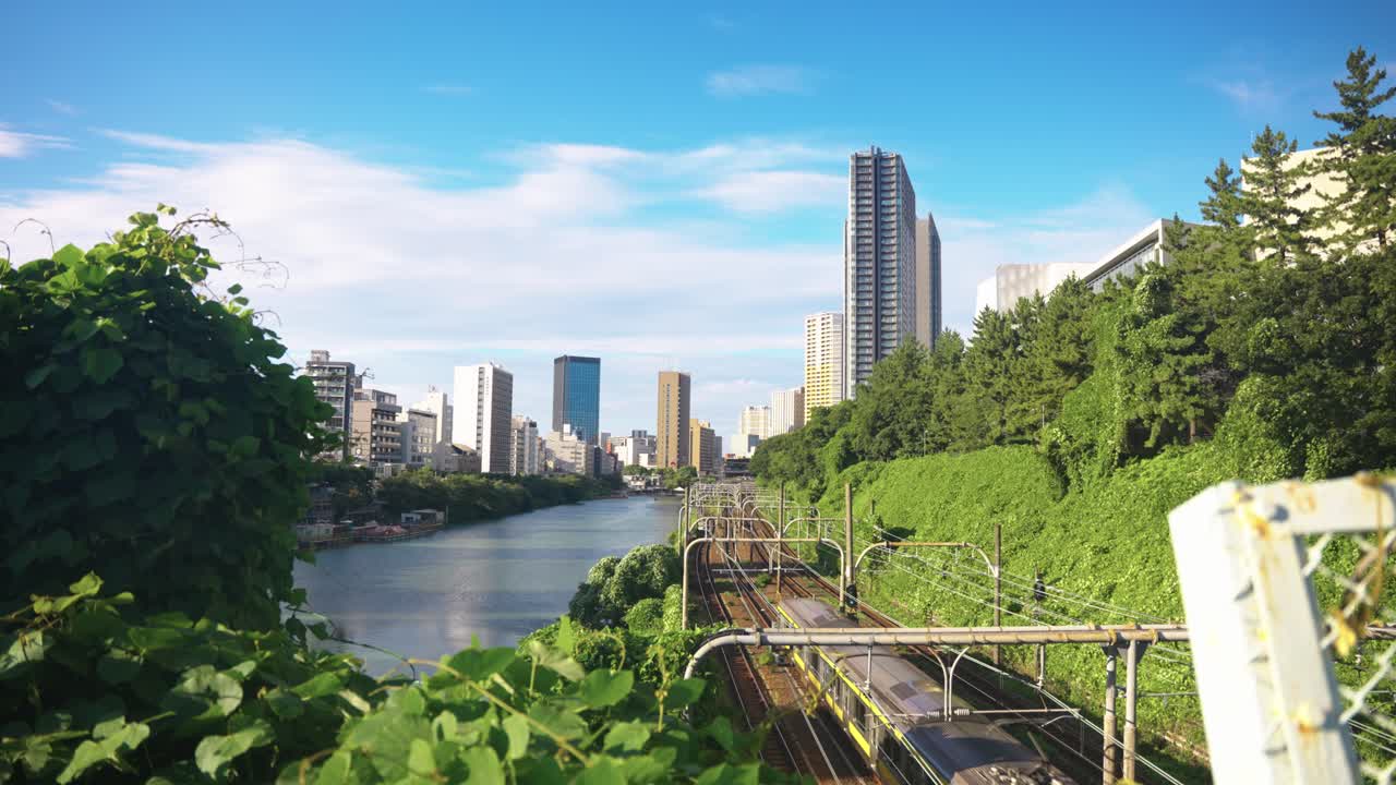 Tokyo Japan, Long JR Train Traveling Past River With City Background
