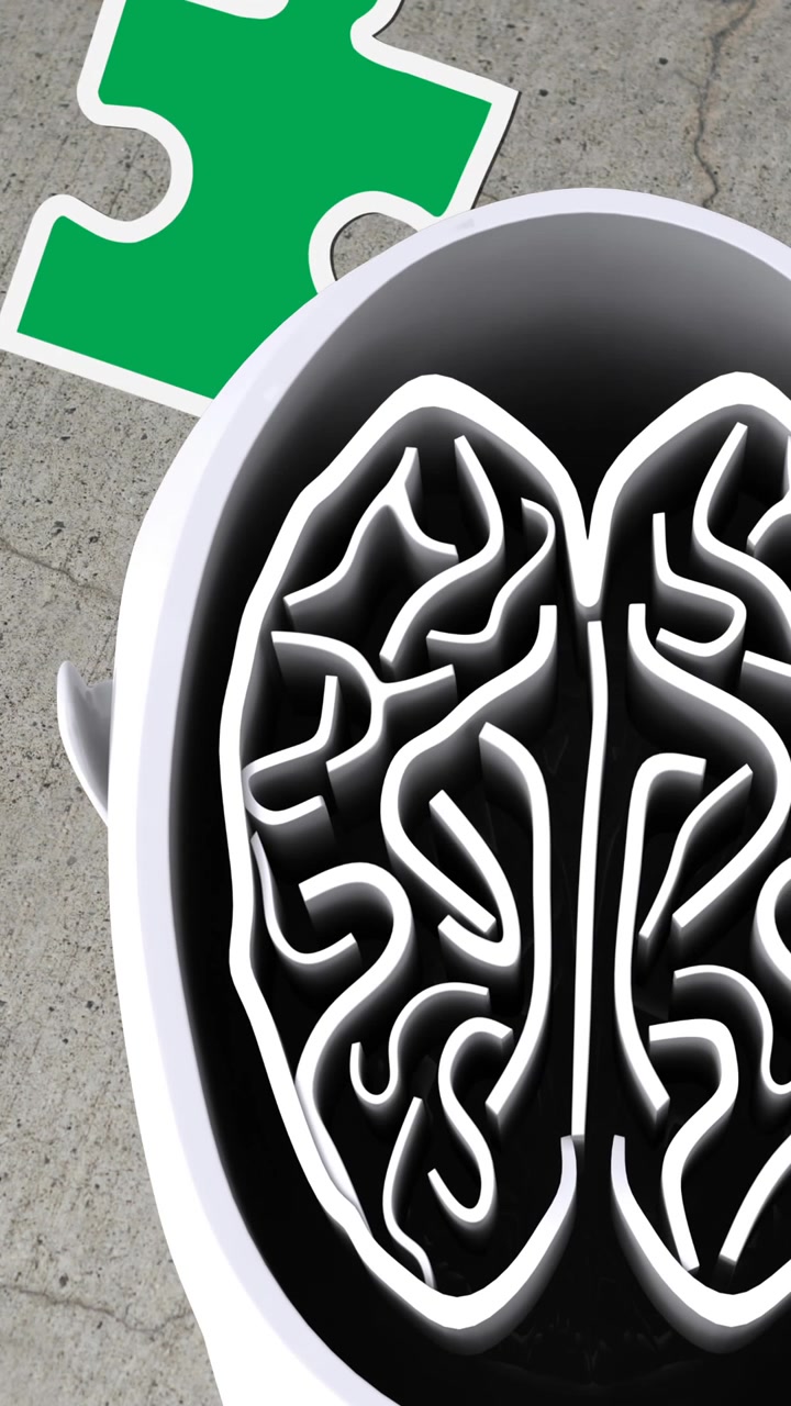Animation of green, yellow and red puzzle pieces falling over model of human head on grey background