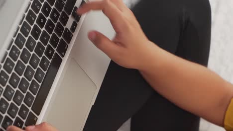 manos de un joven escribiendo en un teclado de computadora portátil