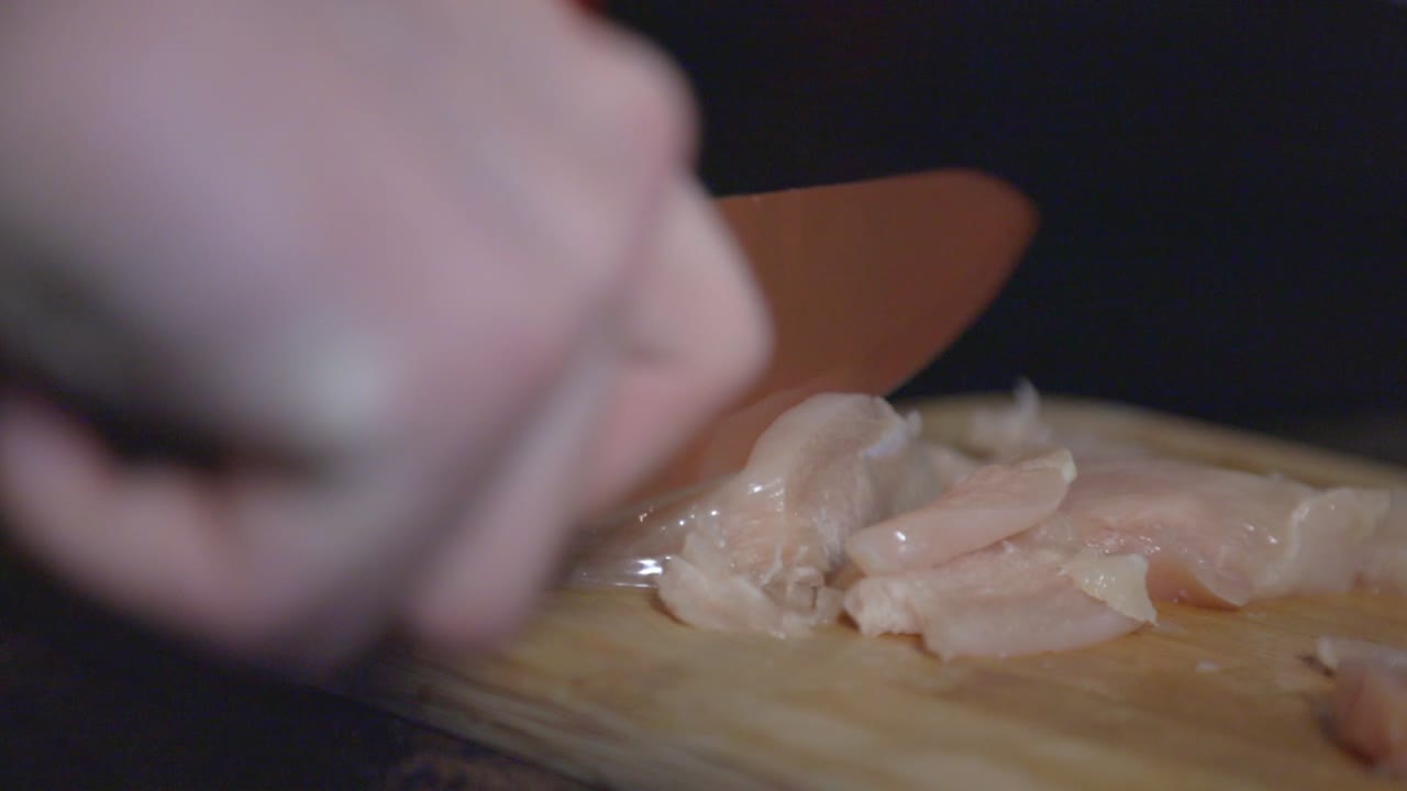 Slicing Chicken Breast Fillet Into Strips On The Wooden Chopping Board. - close up shot