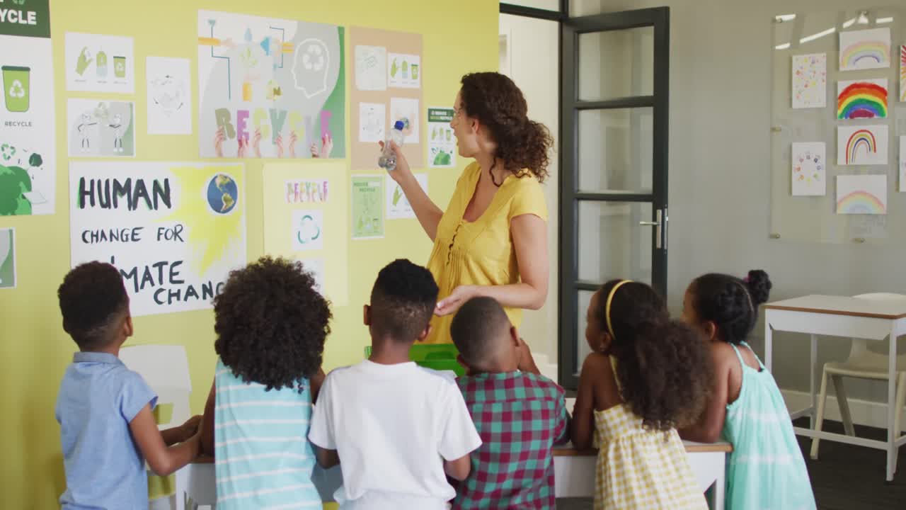 Video of happy caucasian female teacher and class of diverse pupils studying ecology in classroom