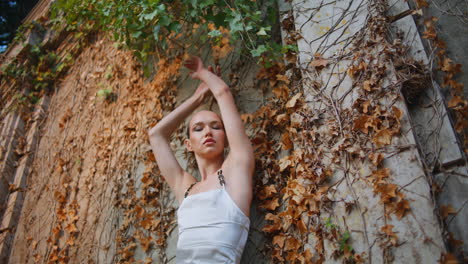 attractive model raising hands posing at old building. sexy woman leaning wall