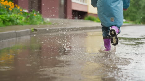 una chica joven saltando en un charco en un día de lluvia