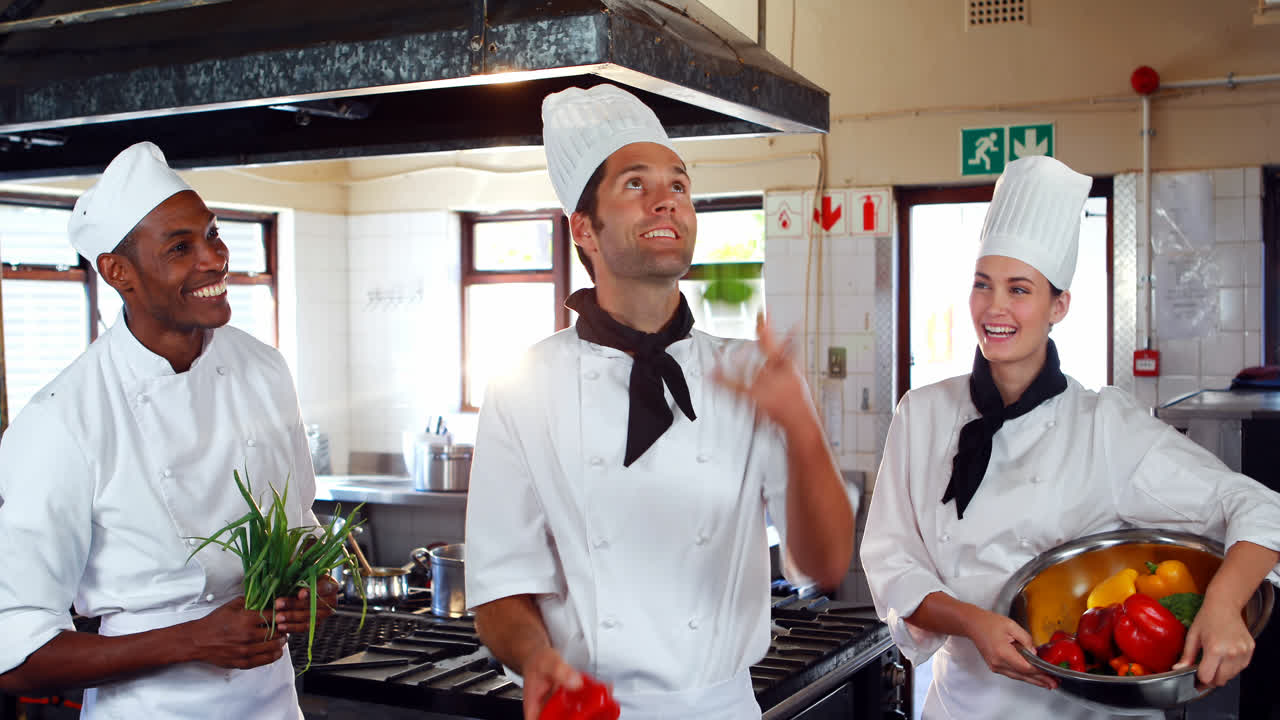 el jefe de cocina haciendo malabarismos con las verduras y los colegas mirando
