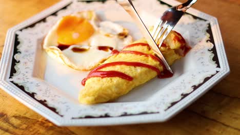 fork and knife cutting omelette on plate