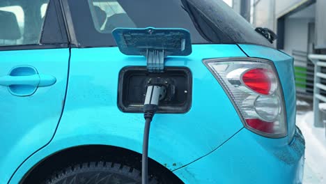 charging light blue color electric vehicle with cable, close up motion view