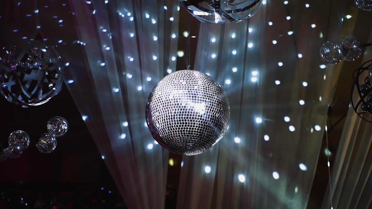 Silver shining disco ball. Mirror ball hanging from the ceiling and spinning against beautiful lights. Entertainment concept.