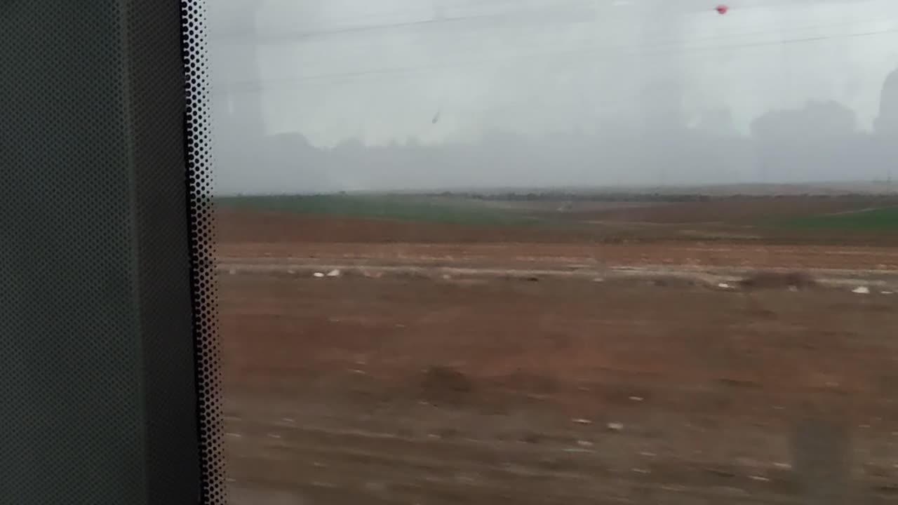 A window view of a road with a field in the background