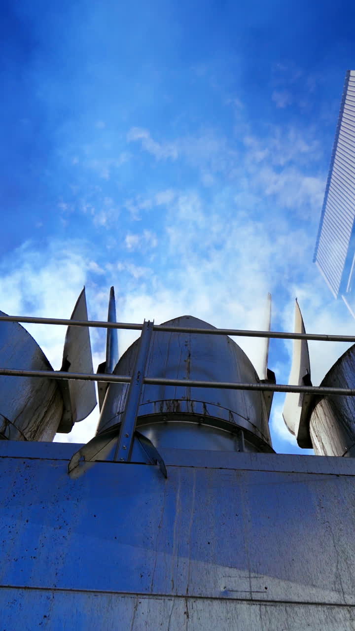 Exterior of warehouse at sunlight. White smoke go into the air from metal pipes of modern granary. Industrial equipment for agribusiness. View from below. Vertical video