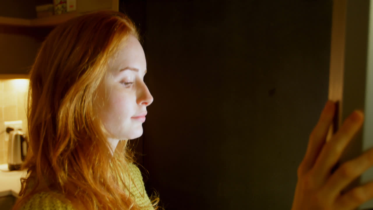 женщина открывает дверь холодильника на кухне 4k