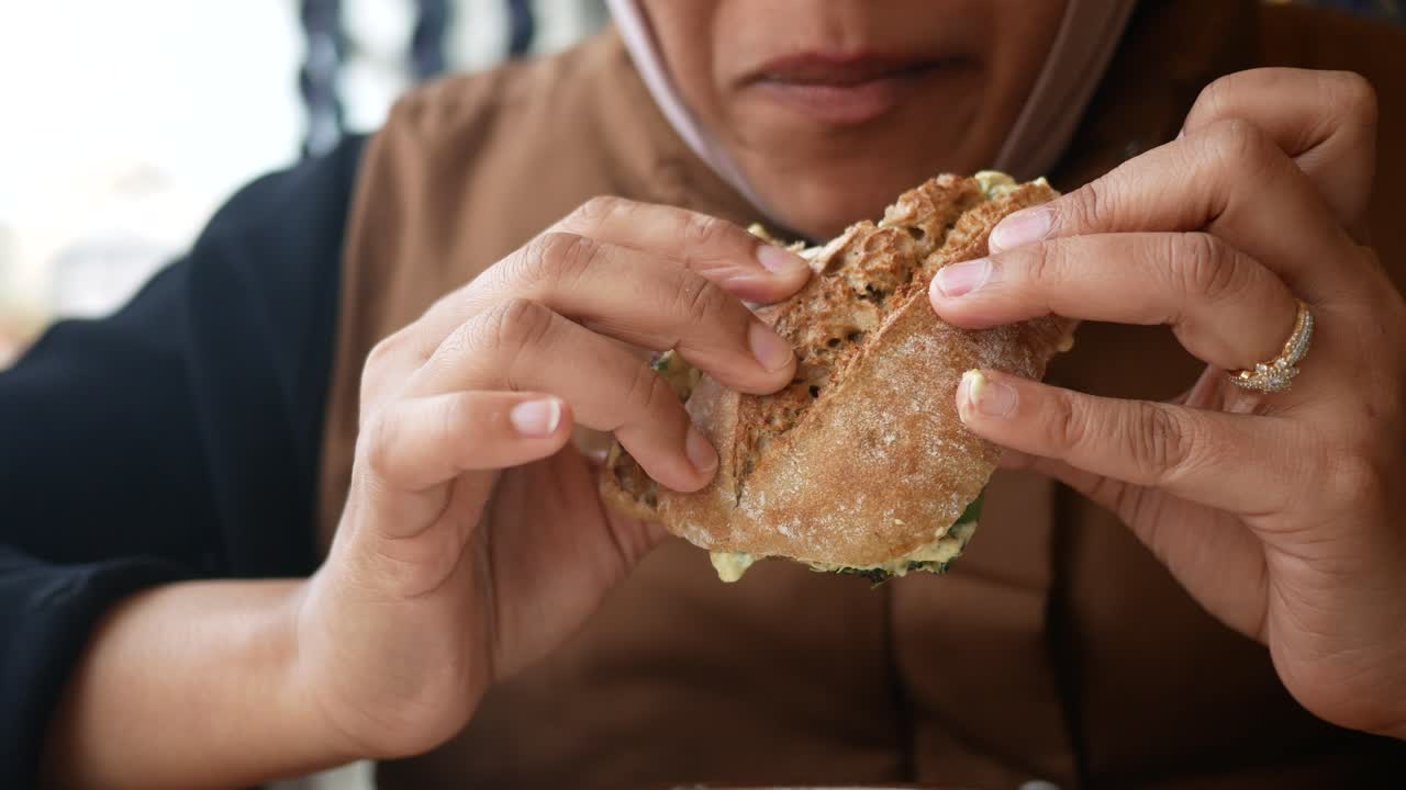 Una mujer comiendo un sándwich.
